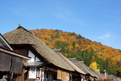 茅葺屋根と紅葉する山